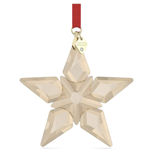 A beige crystal star-shaped festive ornament with a red hanging ribbon and a gold Swarovski branding tag.