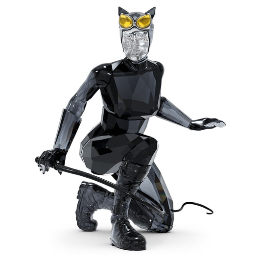 A figurine of Catwoman in a skintight catsuit with a mask, cat-eye goggles, gloves, chunky boots, and a whip, featuring clear, black, and yellow crystal details with lacquered and nickel-coated metal accents.