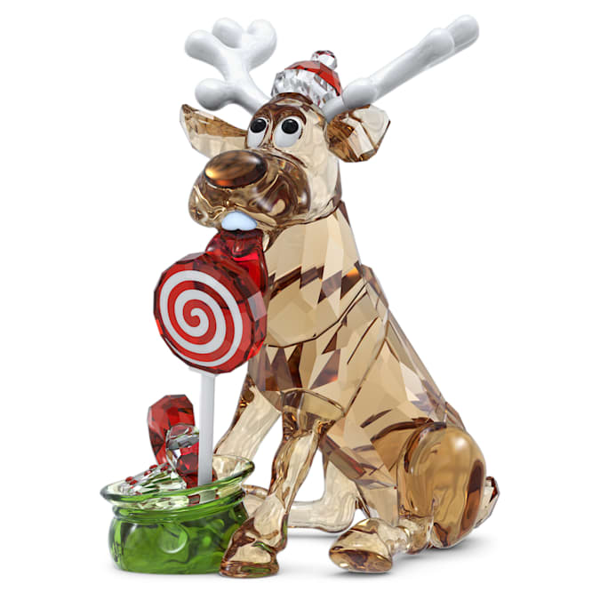A crystal figurine of a reindeer with antlers, wearing a Santa hat, sitting next to a green base and a red and white swirl lollipop.