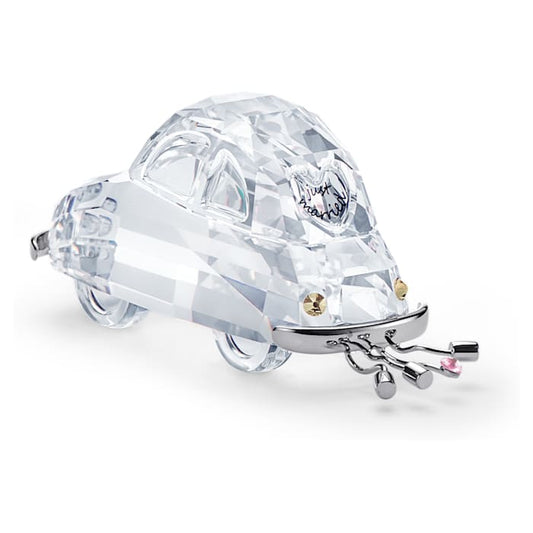 A clear crystal figurine of a car with 'Just Married' text on the back, decorated with strands representing tin cans traditionally tied to the back of a newlyweds' car.
