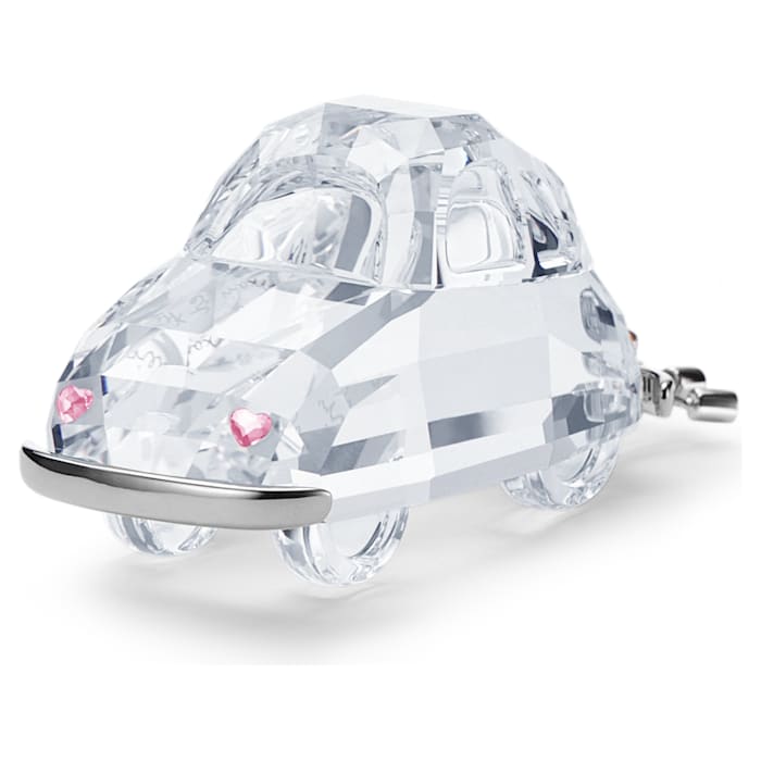 A clear crystal figurine of a car with pink hearts.