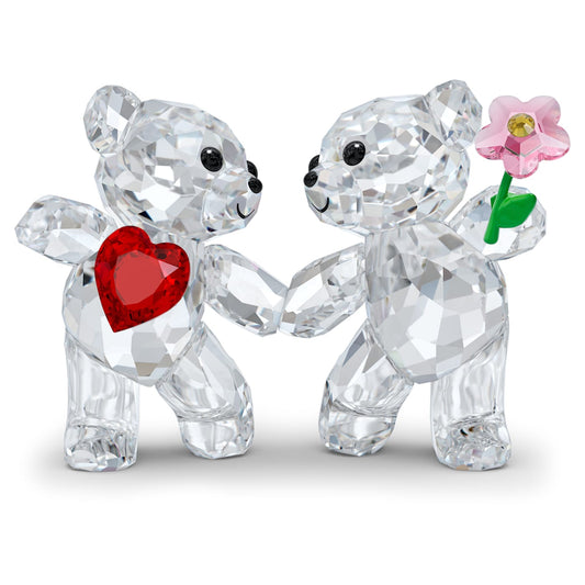 A pair of clear crystal figurines of bears holding red and pink crystal hearts and flowers.