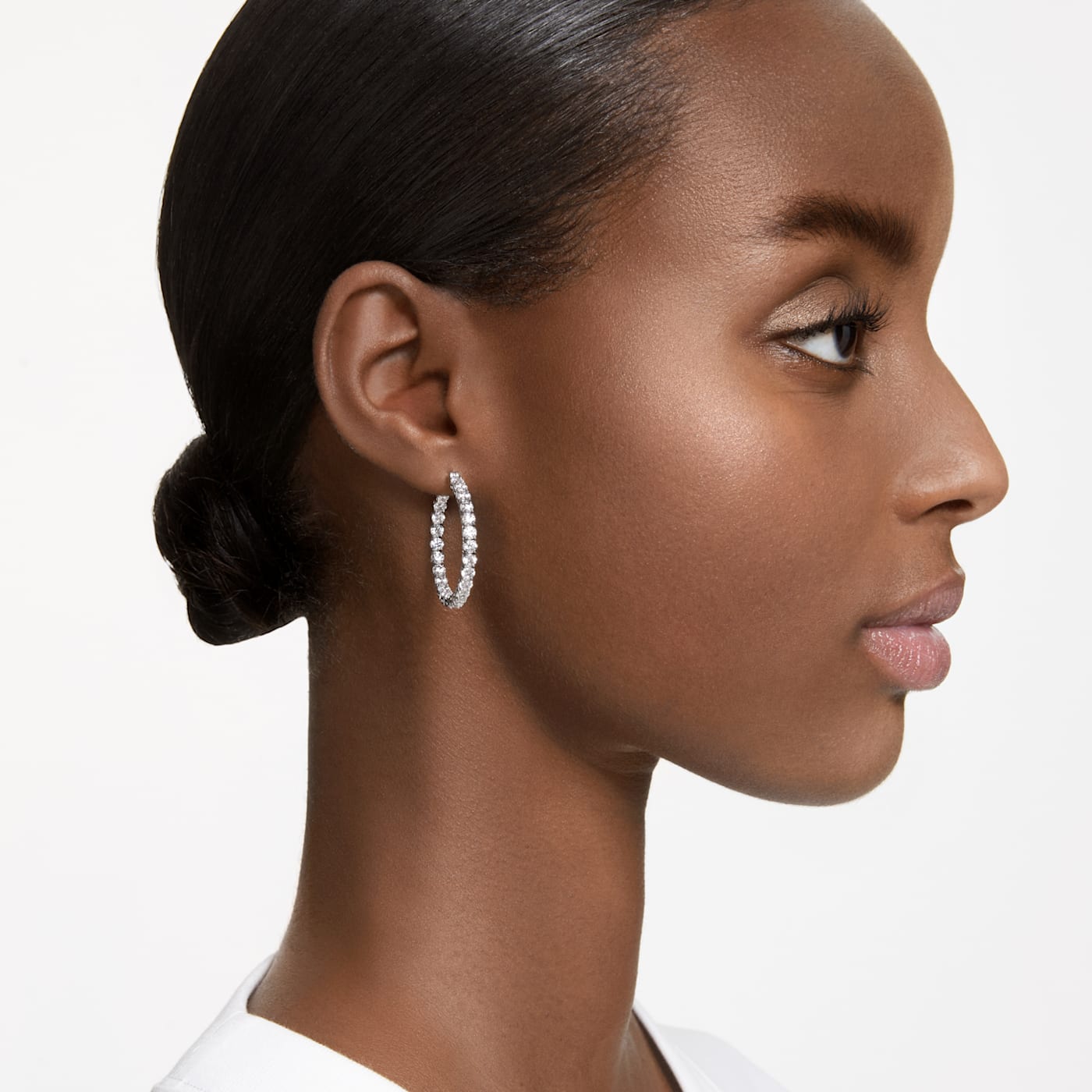 A model is wearing a A rhodium-plated, clear round zirconia hoop earring.