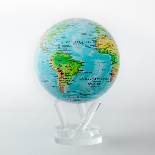 A blue and green globe with lines showing ocean currents, mounted on a clear stand, with visible landmasses and a label for the South Atlantic Ocean.