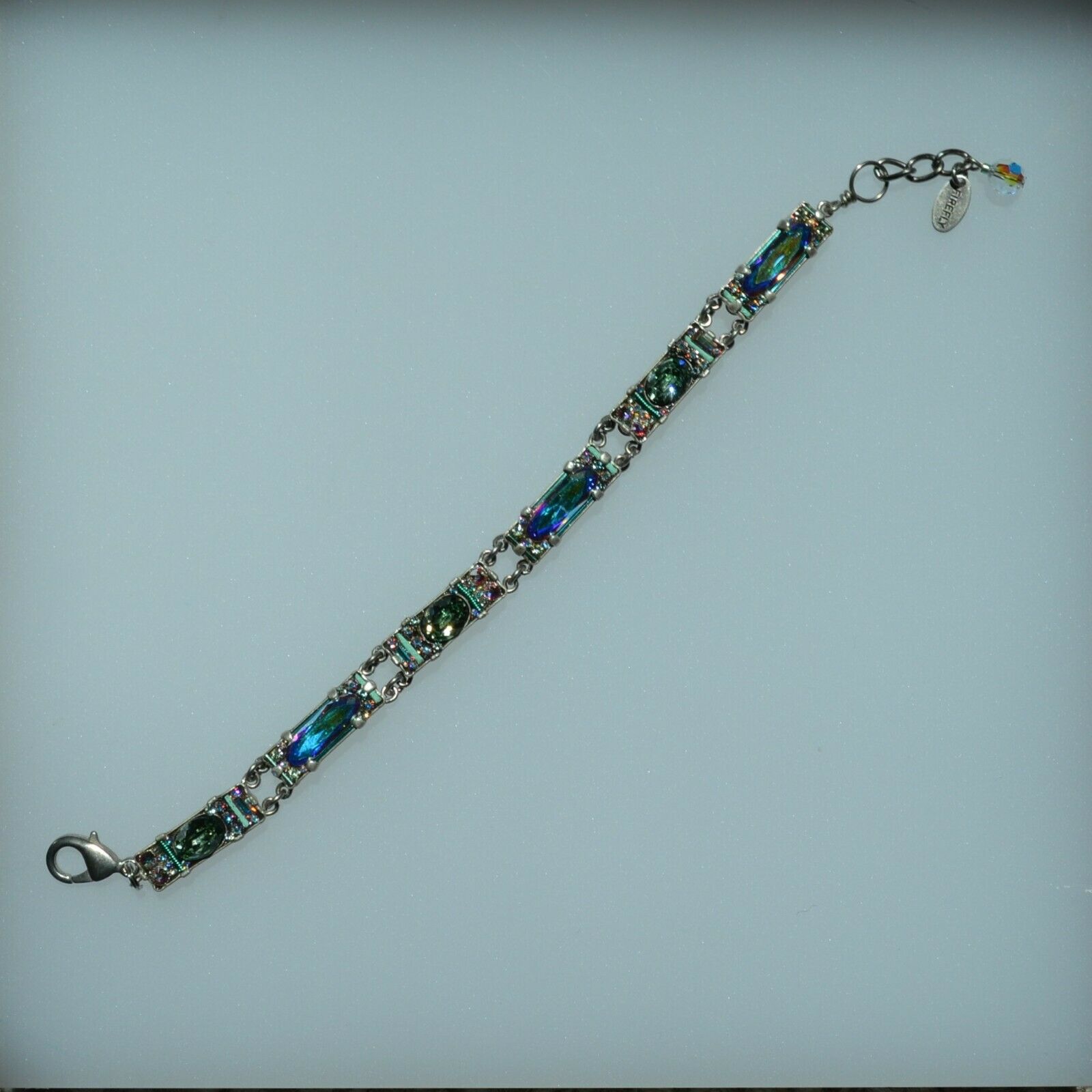 A colorful beaded bracelet with a lobster clasp, featuring a mix of rectangular and oval Swarovski crystals in a rainbow array of colors on a silver-plated brass base