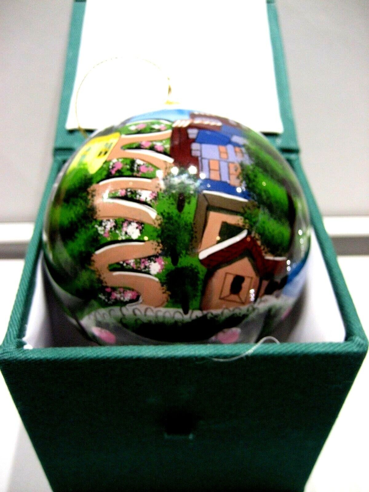 A round decorative ornament depicting a stylized San Francisco scene with the crooked street, placed in a green-trimmed box.