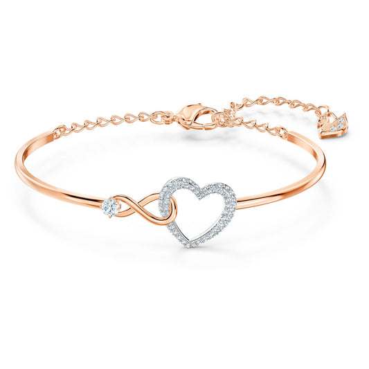 A Swarovski Infinity bangle bracelet featuring a white heart motif and infinity symbol, with a mixed metal finish.