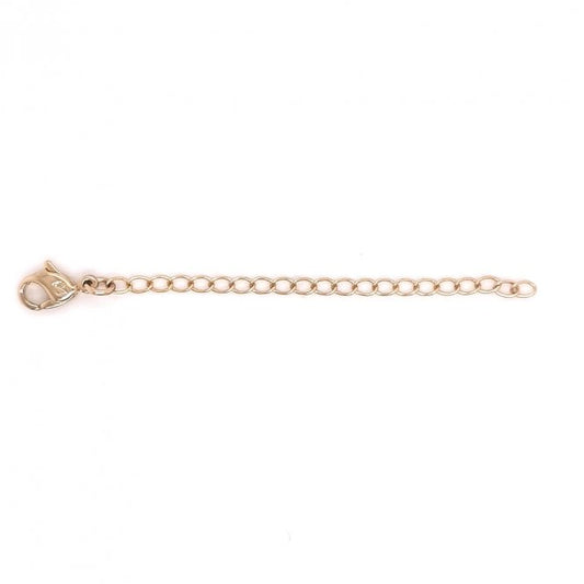 A rose gold-colored Swarovski chain extender lying on a plain background.